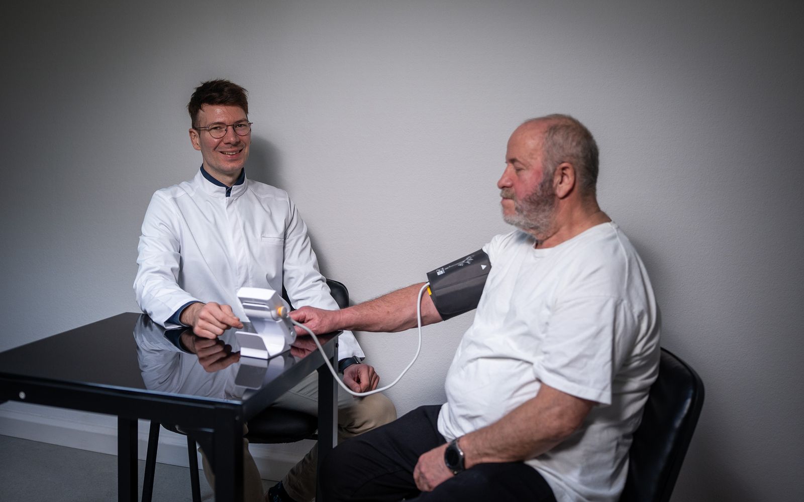 Apotheker der Knut-Apotheke misst bei einem älteren Mann den Blutdruck