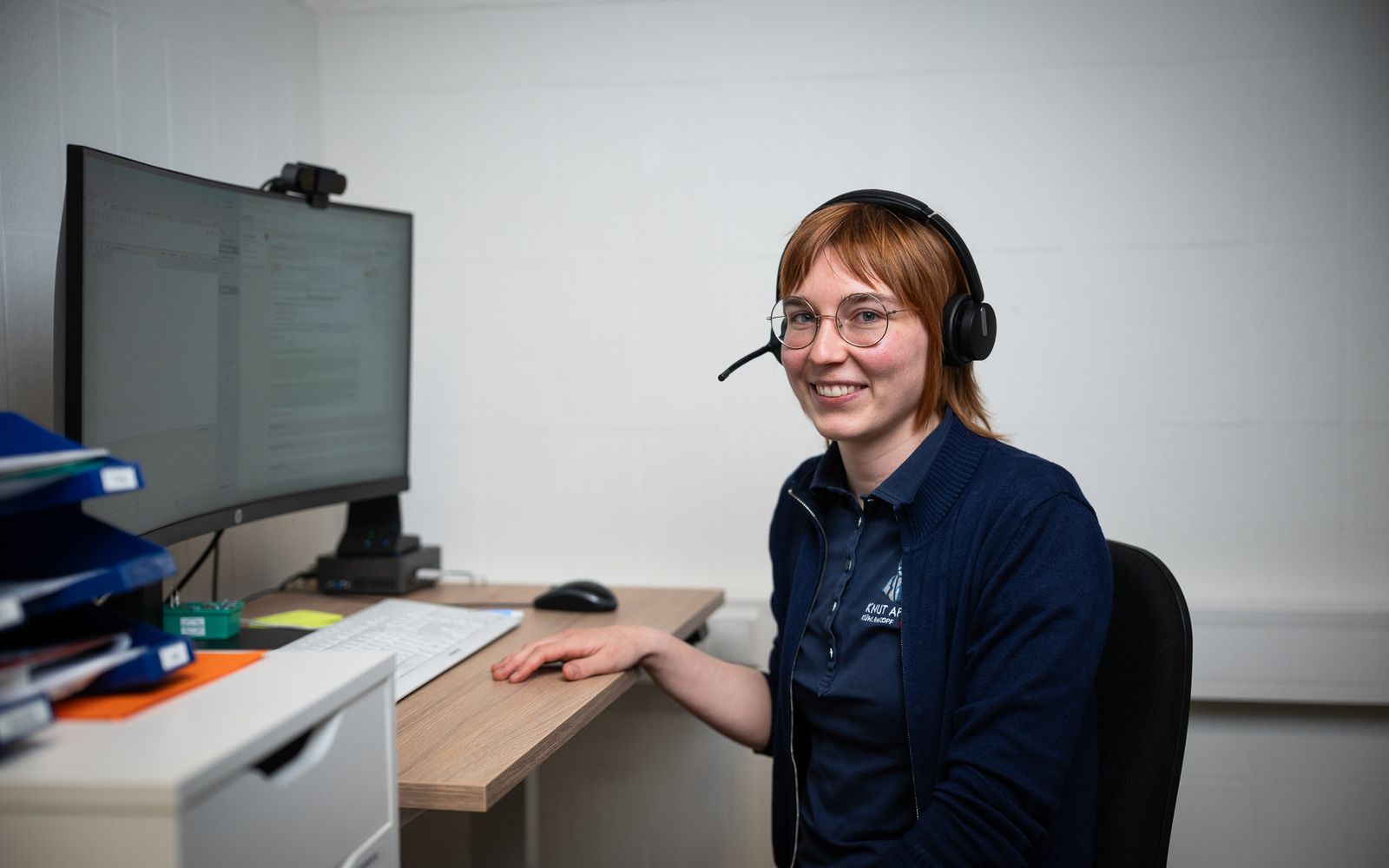 Mitarbeiterin mit Headset an ihrem Arbeitsplatz im Büro der Knut-Apotheke