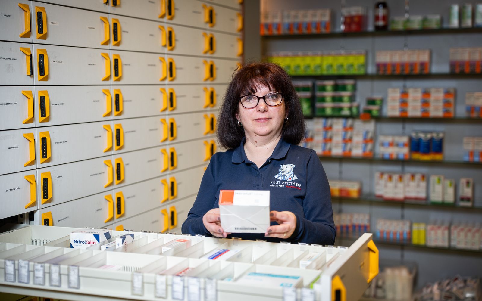 PKA der Knut-Apotheke hält an der Kommissionierschublade eine Packung in der Hand