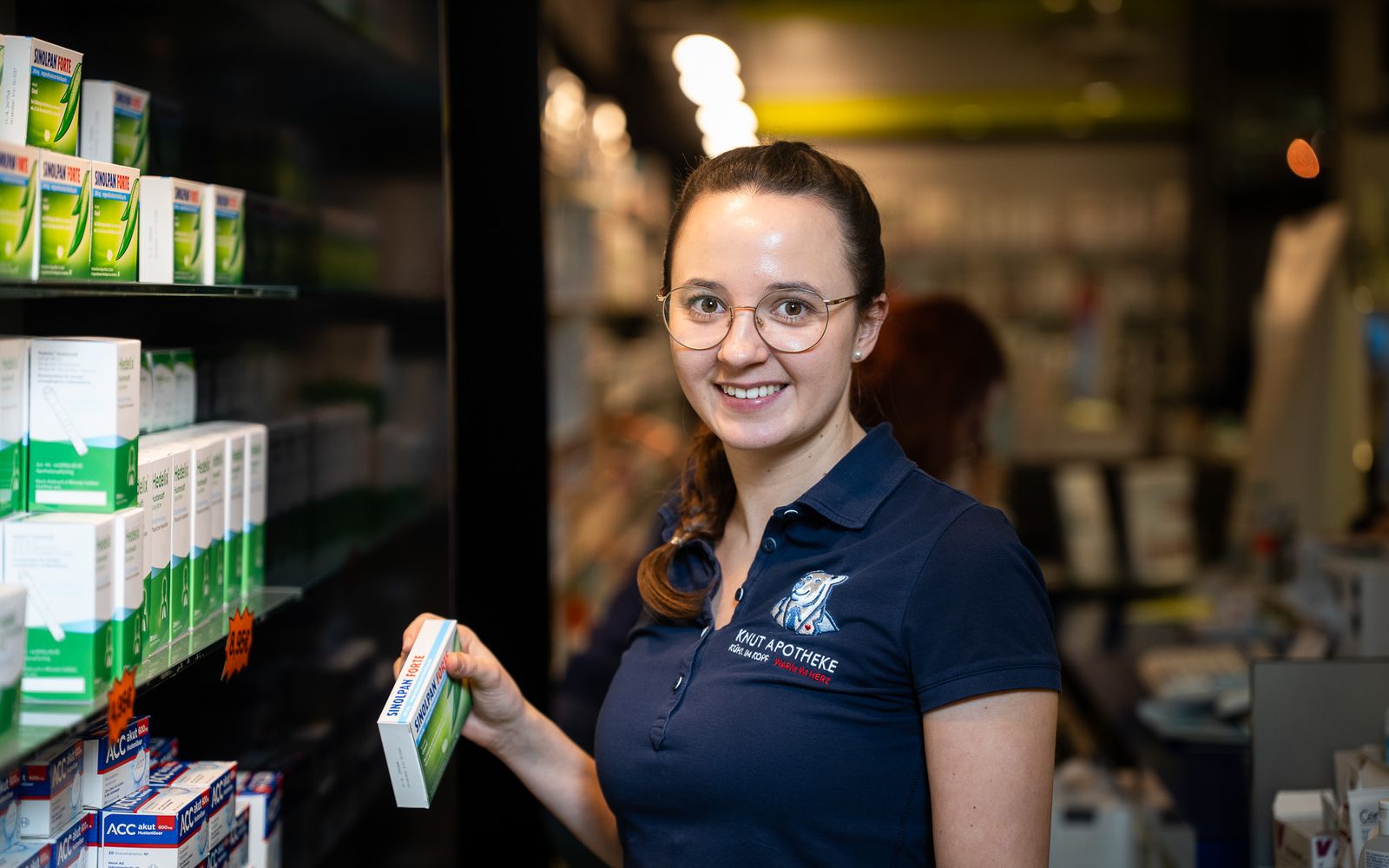 Mitarbeiterin der Knut-Apotheke nimmt eine Packung aus dem Regal